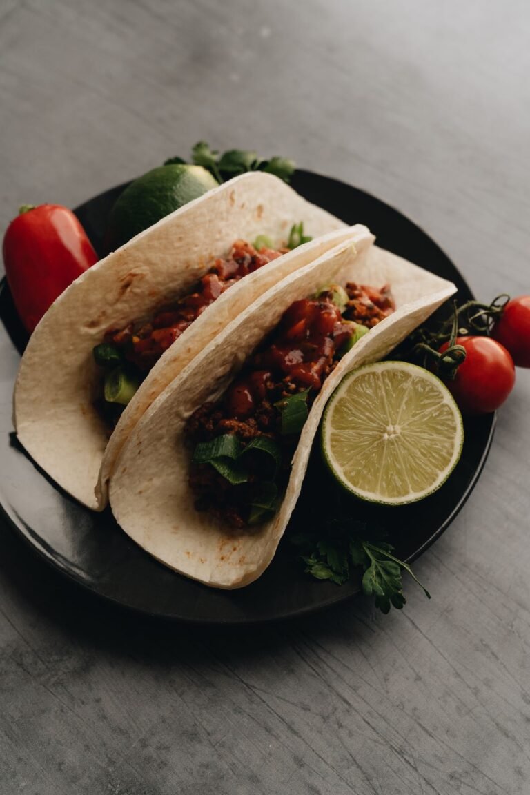 Classic Seasoned Taco Meat (Twice the Dinner) — Flat freezer bag of cooked seasoned taco meat next to warm tortillas and toppings